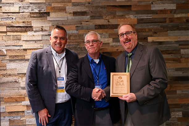 Dennis Brown accepting UAA Partner in Excellence award for Lewis at Trees Utilities Conference 2022